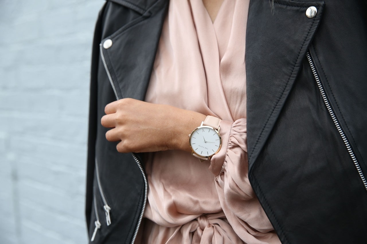 Lady in a silken dress and jacket shows off a glamorous pink watch