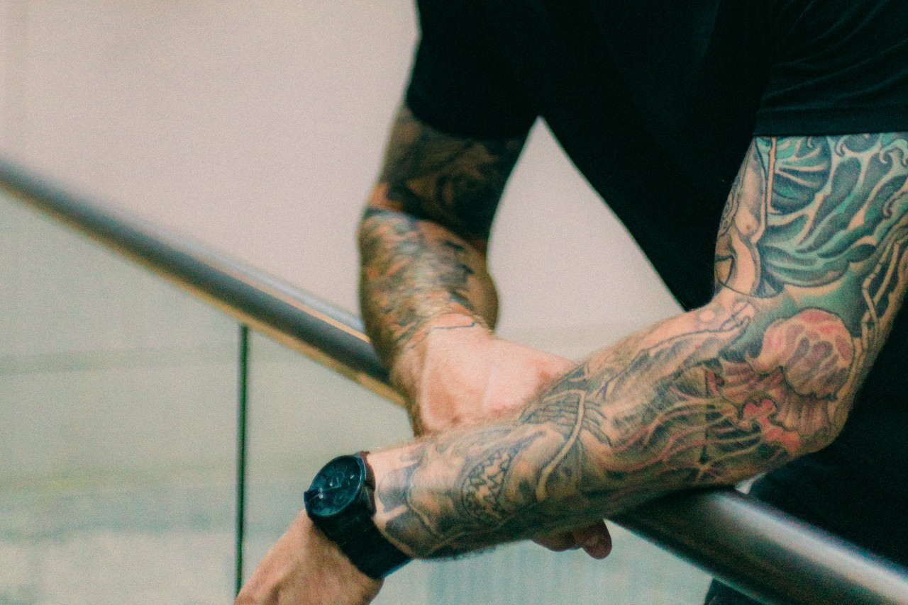 Man with tattoos wearing a black sports watch