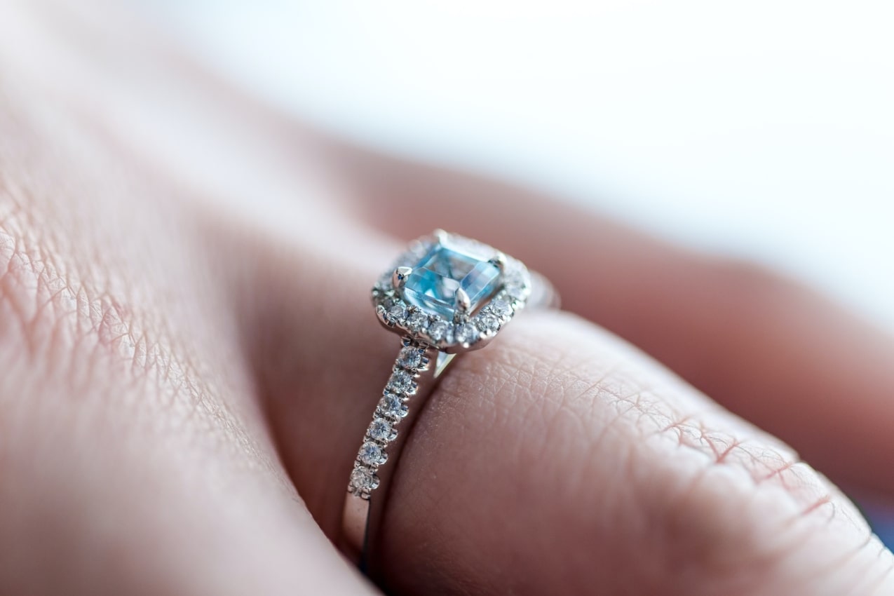 close up image of an engagement ring featuring a light blue center stone
