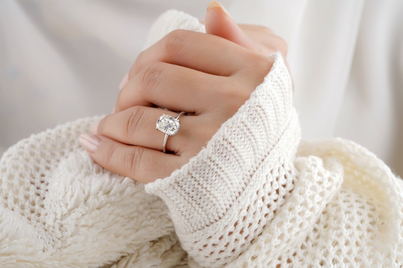 close up image of a woman wearing a white sweater and silver engagement ring