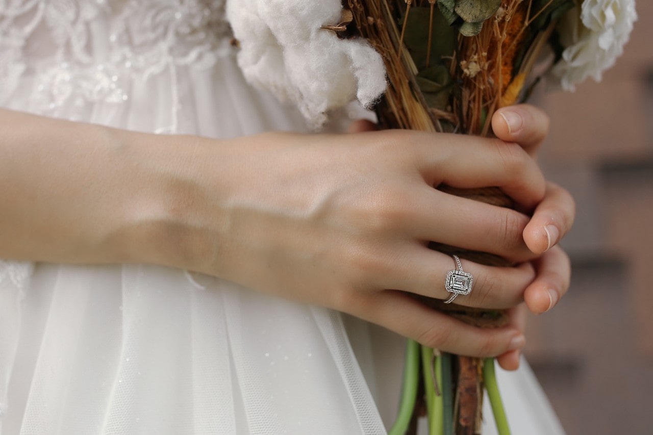a bride holding her bouquet and wearing an emerald cut engagement ring