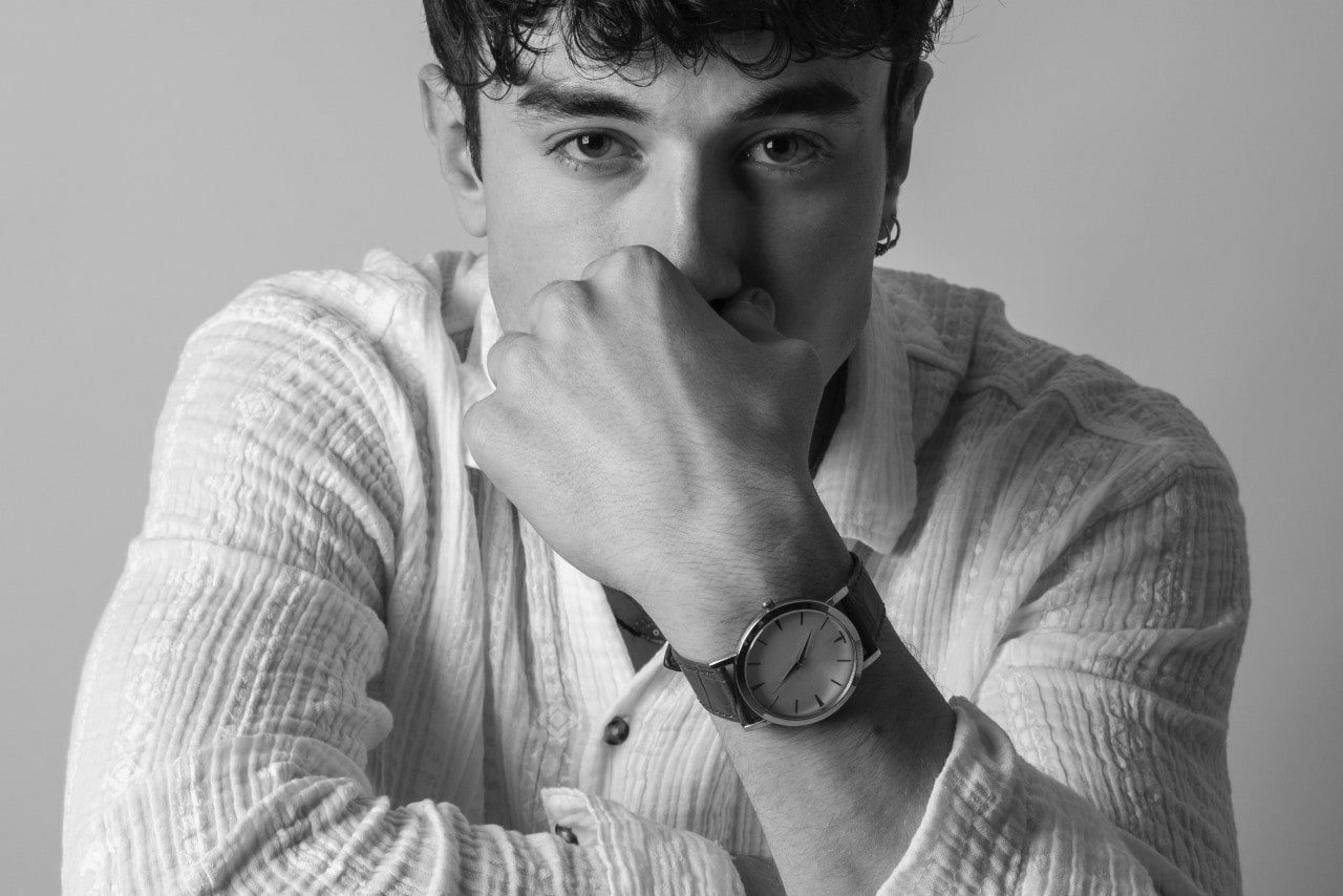 A black and white photo of a man wearing a minimalist luxury watch.