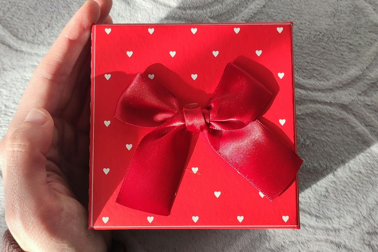 A red box with white hearts and a red bow on top for jewelry this Valentine’s Day