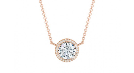 a rose gold necklace featuring a round cut diamond pendant