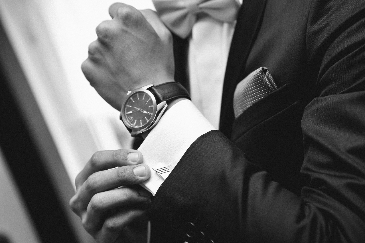 a well-dressed man in a suit revealing his luxury watch