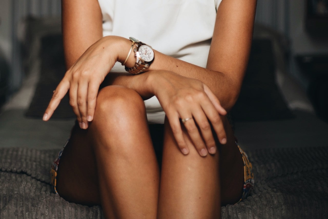 A lady sitting with hands on her lap wearing a luxury watch