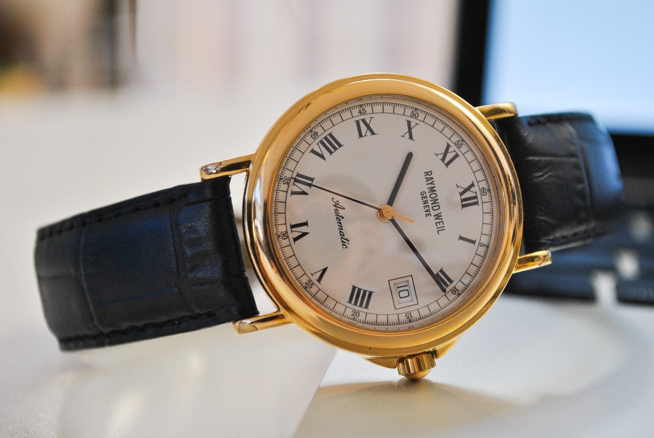 A close-up of a vintage-style Swiss watch laying on its side on a tabletop.