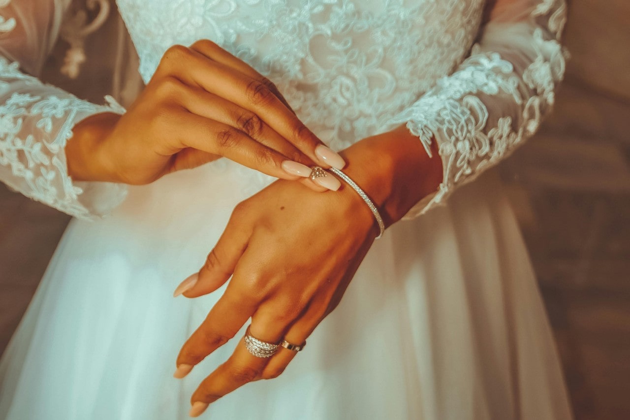 a bride putting on a diamond bracelet while wearing her wedding gown