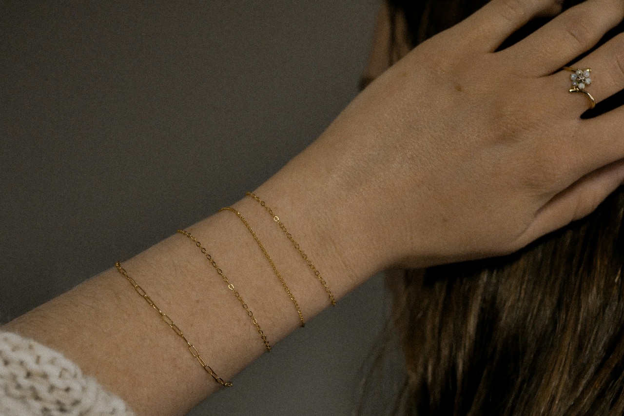 a woman’s hand in her hair, her writs adorned with four fine yellow gold bracelets