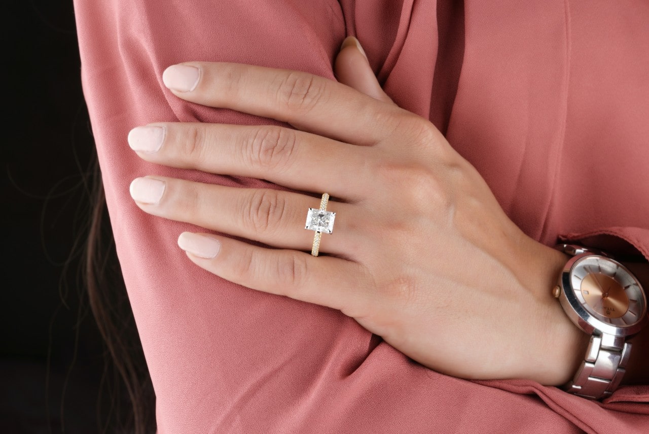 A woman with a beautiful diamond side stone engagement ring set in yellow gold