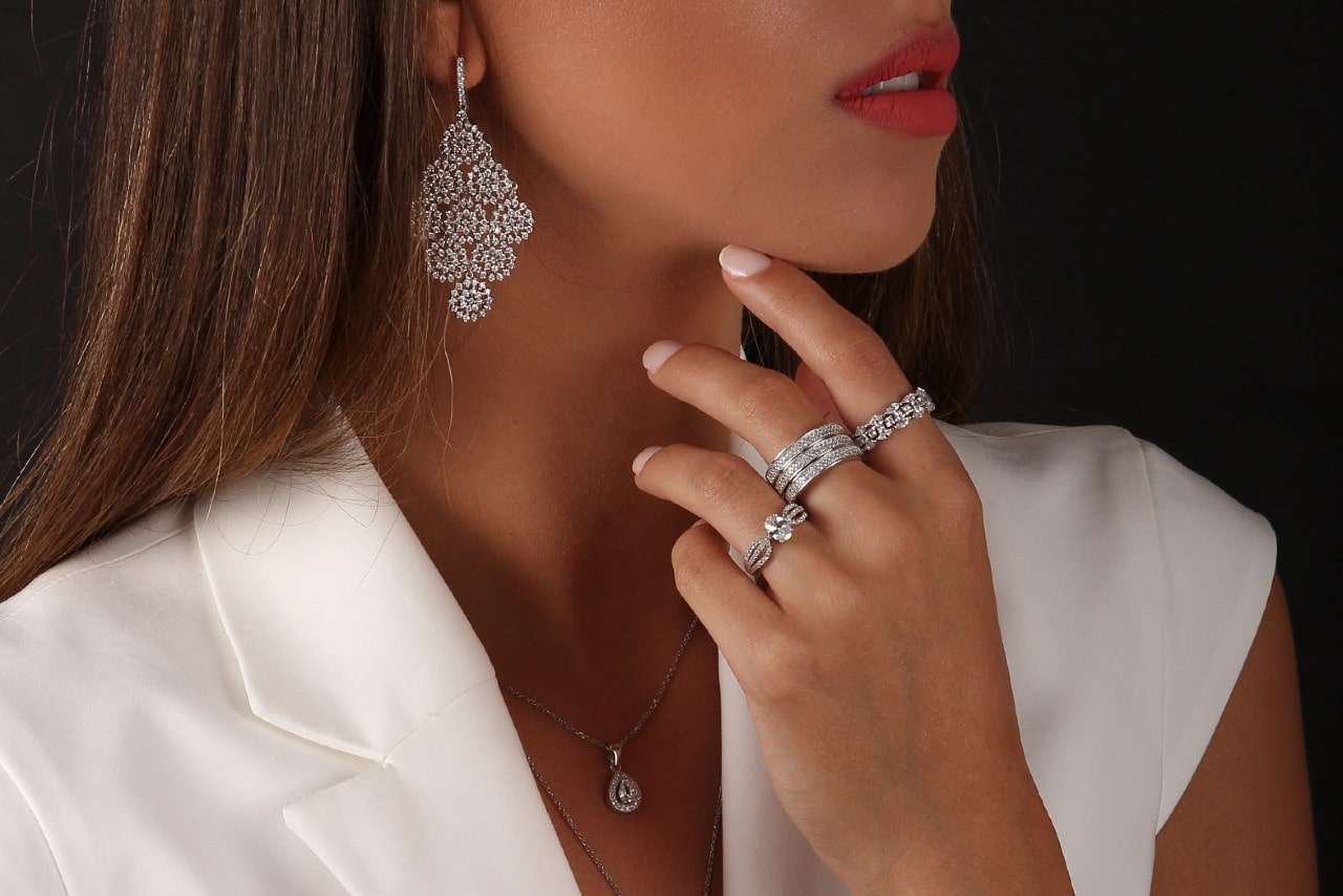 A woman wearing diamond earrings, rings and necklace.